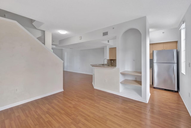 kitchen featuring light hardwood / wood-style floors, light brown cabinets, stainless steel fridge, and sink