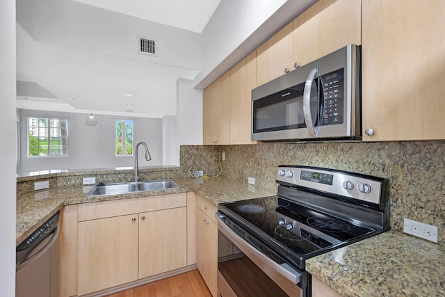 kitchen featuring a sink, light brown cabinetry, stainless steel appliances, and visible vents