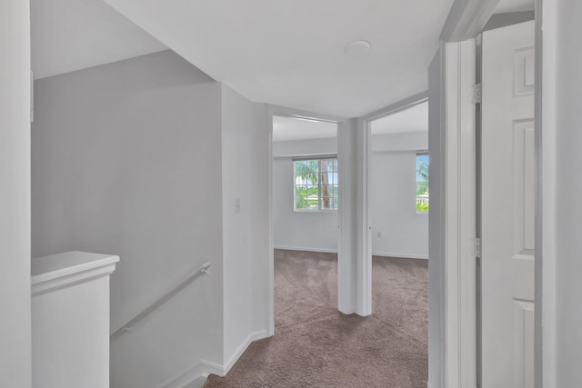 hall featuring baseboards, carpet flooring, and an upstairs landing