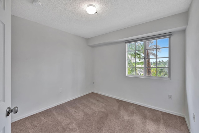 empty room with carpet floors, a textured ceiling, and baseboards