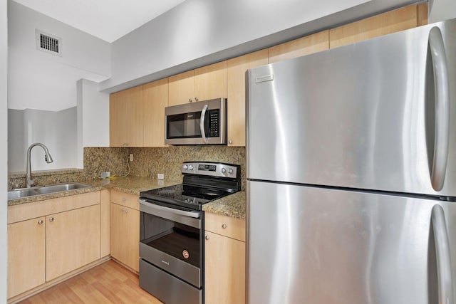 kitchen featuring visible vents, decorative backsplash, light brown cabinets, a sink, and appliances with stainless steel finishes