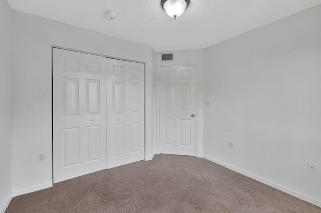 unfurnished bedroom with carpet floors, a textured ceiling, and a closet