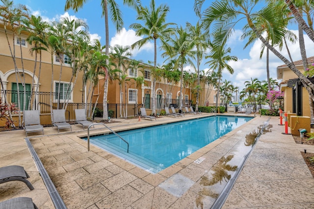 pool with a patio area and fence