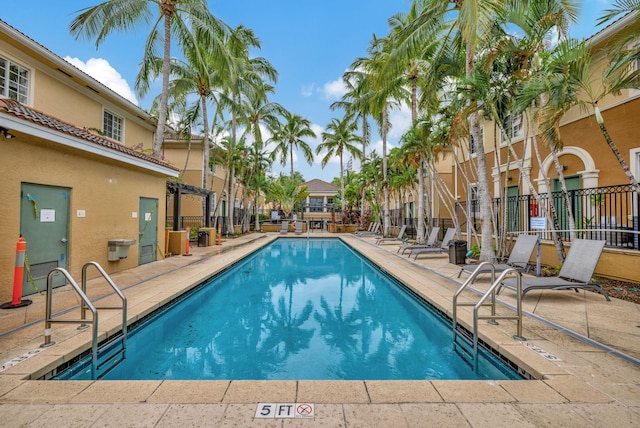community pool featuring fence, a residential view, and a patio area