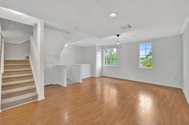 unfurnished living room featuring baseboards, visible vents, ornamental molding, and light wood-type flooring