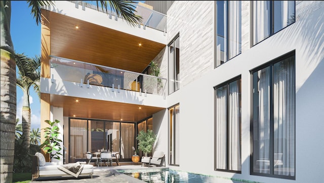 rear view of property with a patio area, a pool, and a balcony
