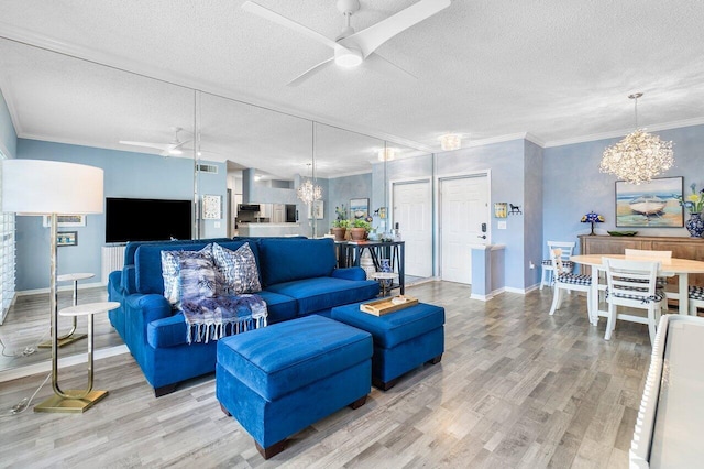 living room with hardwood / wood-style floors, ceiling fan with notable chandelier, crown molding, and a textured ceiling