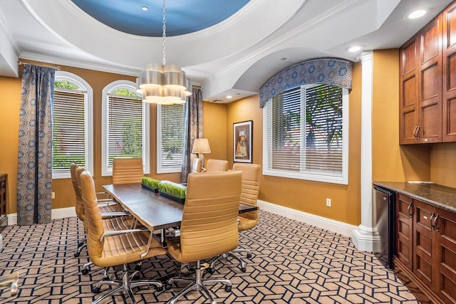 carpeted dining space with a chandelier, a healthy amount of sunlight, ornamental molding, and a tray ceiling