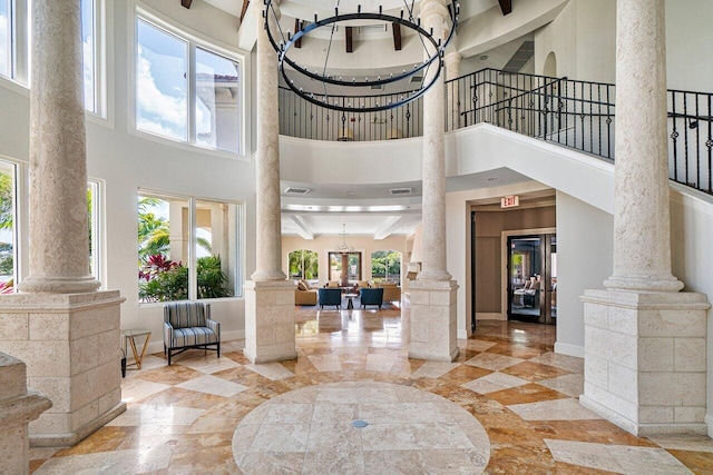 foyer entrance featuring plenty of natural light, ornate columns, and a high ceiling