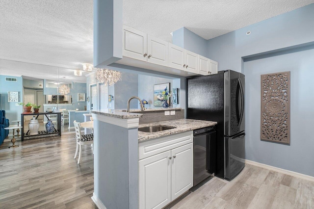 kitchen with kitchen peninsula, a textured ceiling, sink, black appliances, and white cabinets