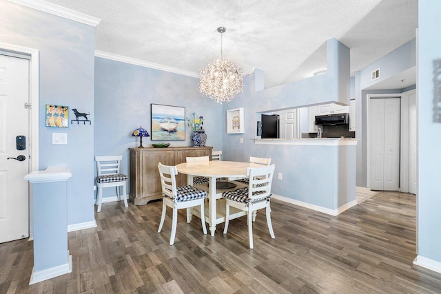 dining room with dark hardwood / wood-style flooring, ornamental molding, a textured ceiling, and a chandelier