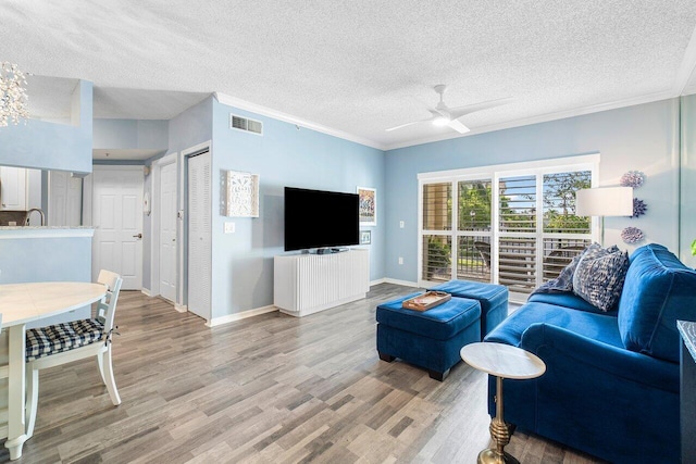 living room with ceiling fan, light hardwood / wood-style floors, a textured ceiling, and ornamental molding