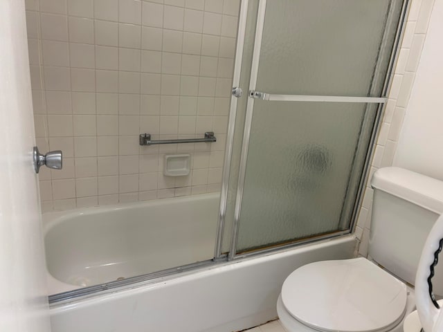 bathroom featuring enclosed tub / shower combo and toilet