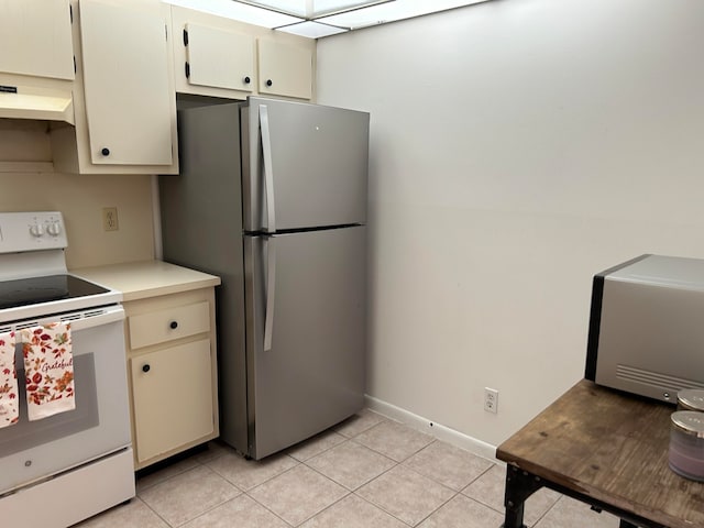 kitchen featuring cream cabinets, stainless steel fridge, exhaust hood, electric range, and light tile patterned floors