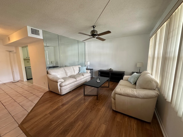 living room with ceiling fan, light hardwood / wood-style floors, and a textured ceiling