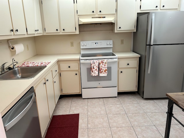 kitchen with cream cabinets, appliances with stainless steel finishes, sink, and light tile patterned floors