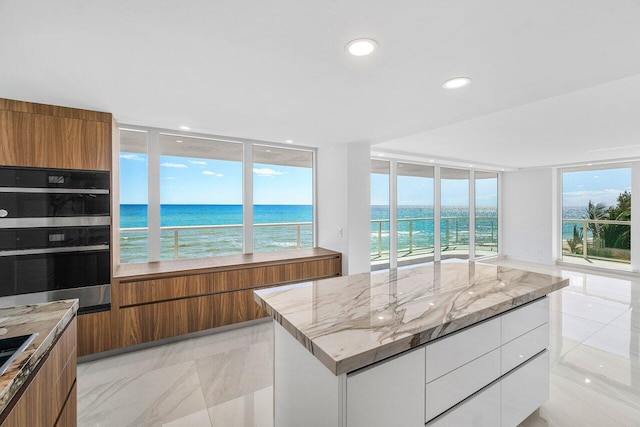 kitchen featuring modern cabinets, brown cabinets, light stone countertops, and stainless steel double oven