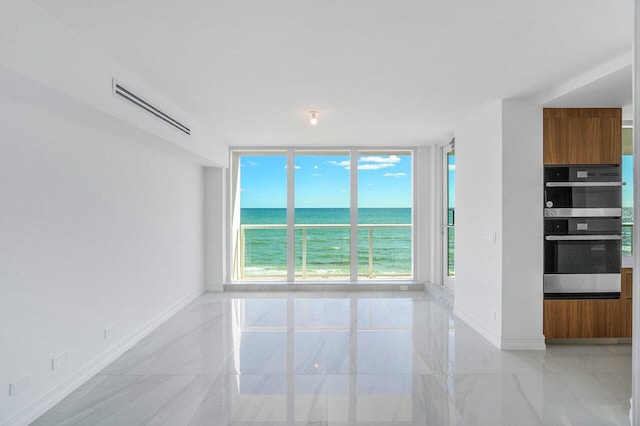 unfurnished room featuring visible vents, baseboards, a water view, expansive windows, and marble finish floor