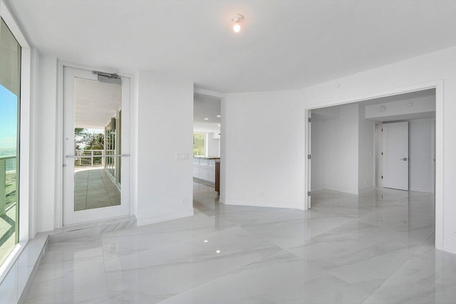 spare room featuring baseboards and marble finish floor