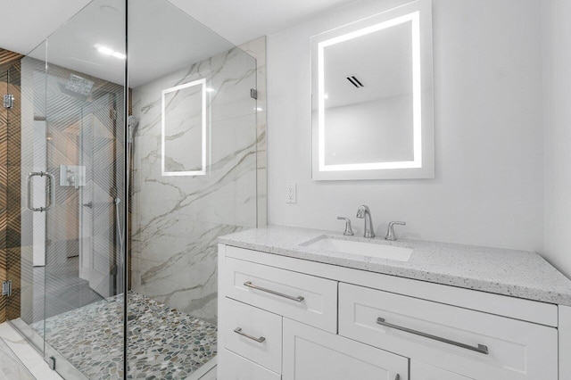 bathroom featuring a shower with door and vanity