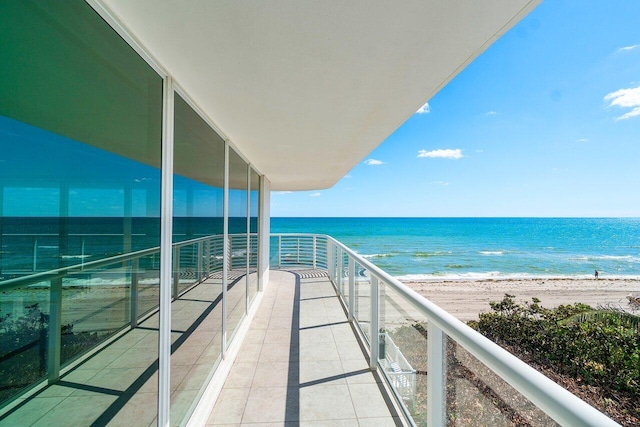 balcony with a water view and a view of the beach