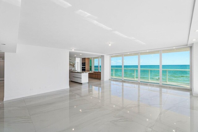 unfurnished living room featuring floor to ceiling windows and a water view