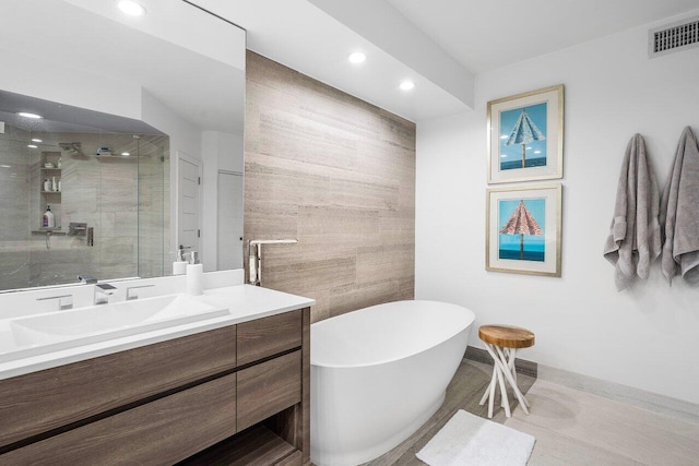 bathroom with plus walk in shower, vanity, and tile walls