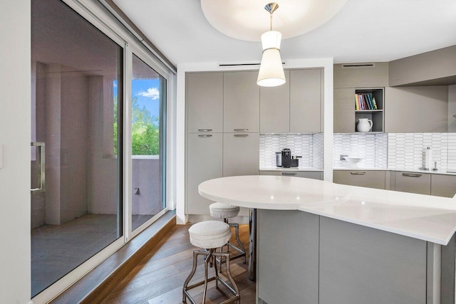 kitchen featuring pendant lighting, backsplash, dark wood-type flooring, and gray cabinetry