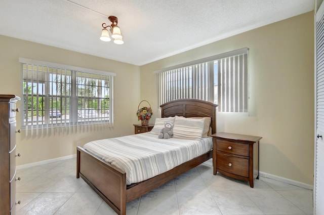 bedroom featuring a closet, a textured ceiling, a notable chandelier, and light tile patterned floors