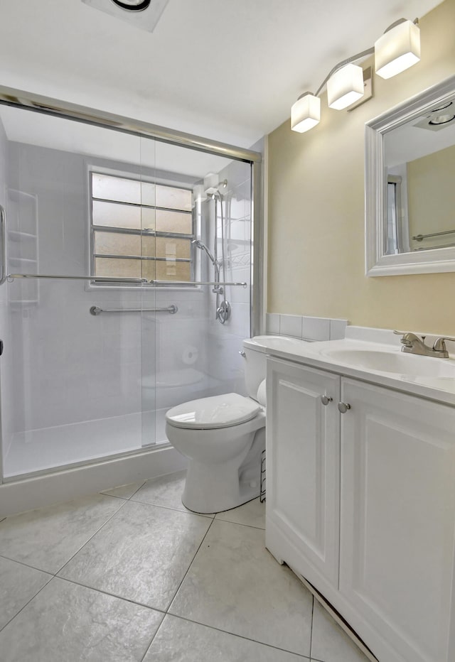 bathroom with toilet, a shower with shower door, vanity, and tile patterned floors