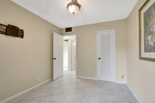 unfurnished bedroom with a closet, a textured ceiling, and light tile patterned flooring