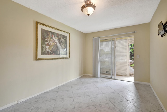 empty room with a textured ceiling and light tile patterned flooring