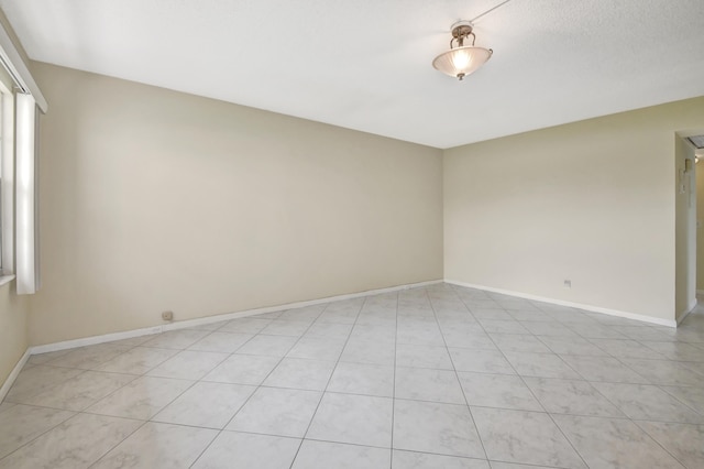 tiled empty room with a textured ceiling