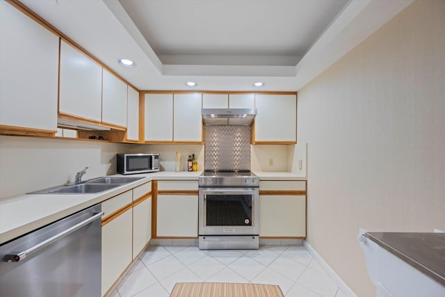 kitchen with light tile patterned floors, sink, white cabinetry, a tray ceiling, and appliances with stainless steel finishes