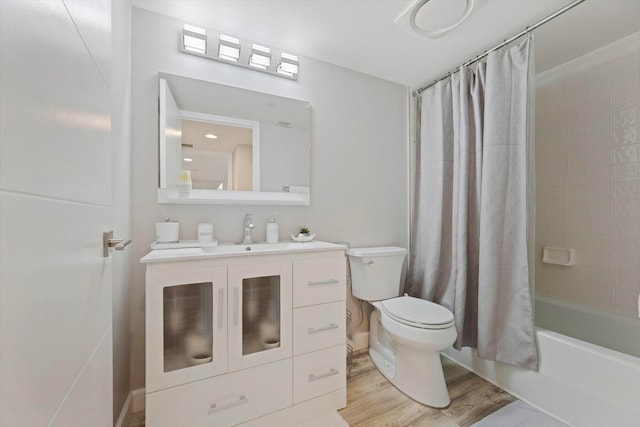 full bathroom with hardwood / wood-style floors, toilet, shower / bath combo with shower curtain, and vanity