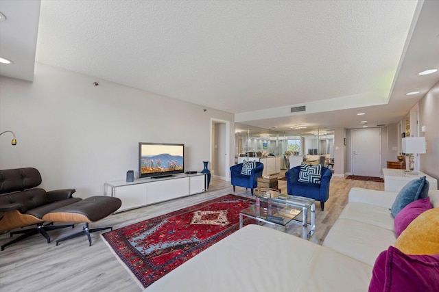 living room with a textured ceiling and light wood-type flooring