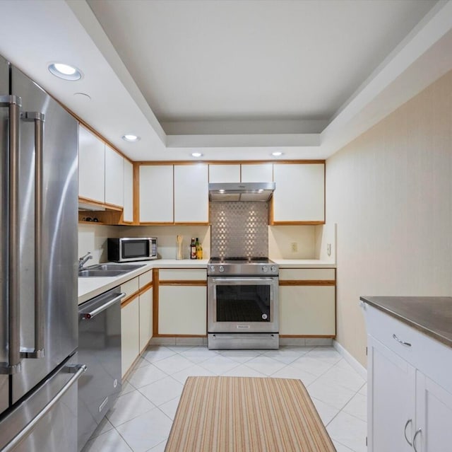 kitchen with stainless steel appliances, light tile patterned flooring, white cabinets, and sink