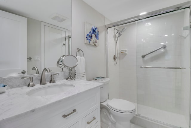 bathroom featuring vanity, a shower with shower door, and toilet