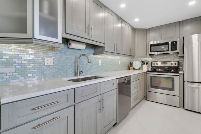 kitchen featuring gray cabinetry, sink, decorative backsplash, appliances with stainless steel finishes, and light tile patterned floors