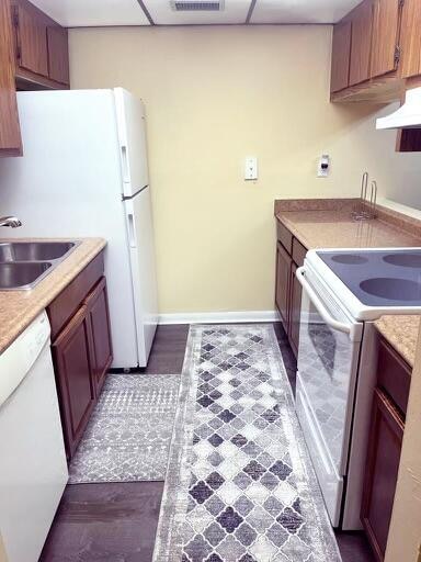 kitchen featuring dark wood-type flooring, white appliances, and sink