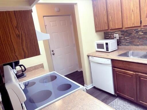 kitchen featuring dark wood-type flooring, tasteful backsplash, and white appliances