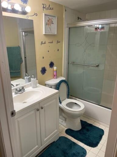 full bathroom featuring tile patterned flooring, shower / bath combination with glass door, vanity, and toilet