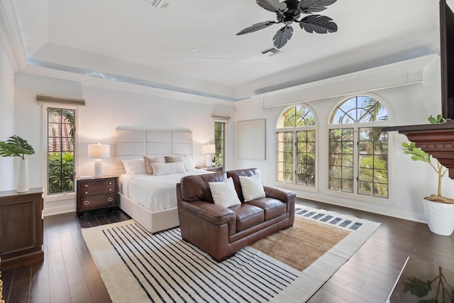 bedroom featuring dark hardwood / wood-style floors, ceiling fan, ornamental molding, and a tray ceiling