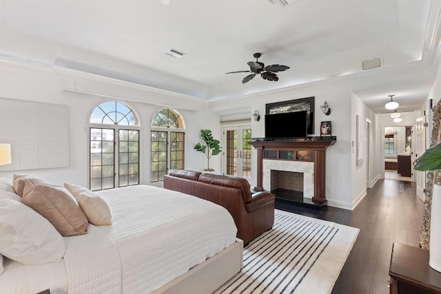 bedroom with a premium fireplace, multiple windows, dark wood-type flooring, and ceiling fan