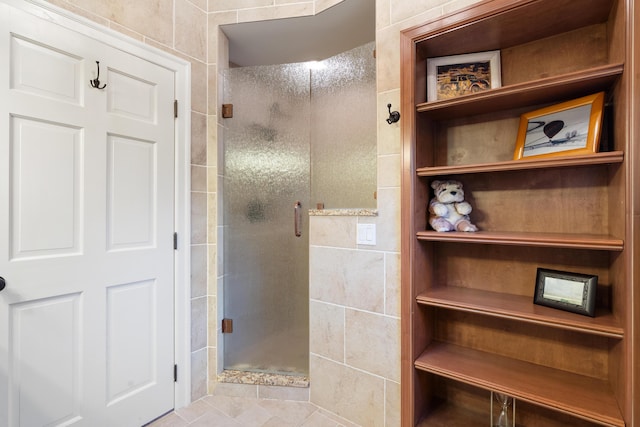 bathroom featuring tile patterned floors, a shower with door, and tile walls