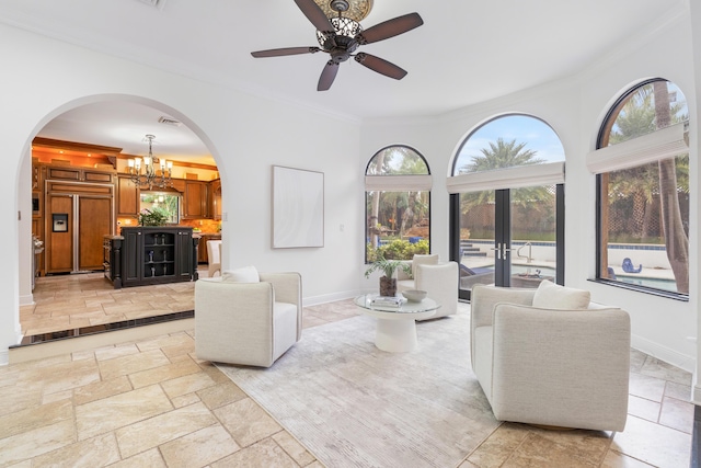 living room with french doors, ceiling fan with notable chandelier, and ornamental molding