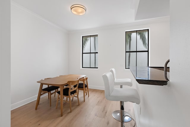 dining area featuring light wood-type flooring and crown molding