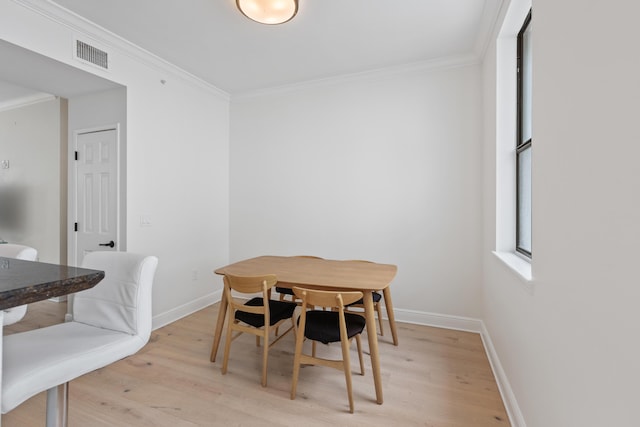 dining space featuring light hardwood / wood-style floors and crown molding