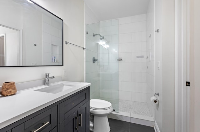 bathroom with toilet, a tile shower, tile patterned flooring, and vanity