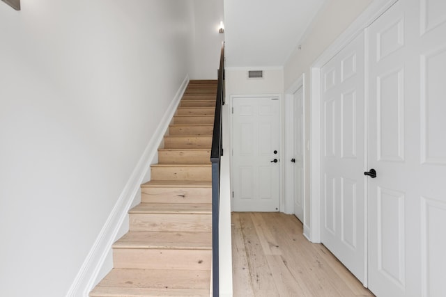 staircase featuring crown molding and wood-type flooring